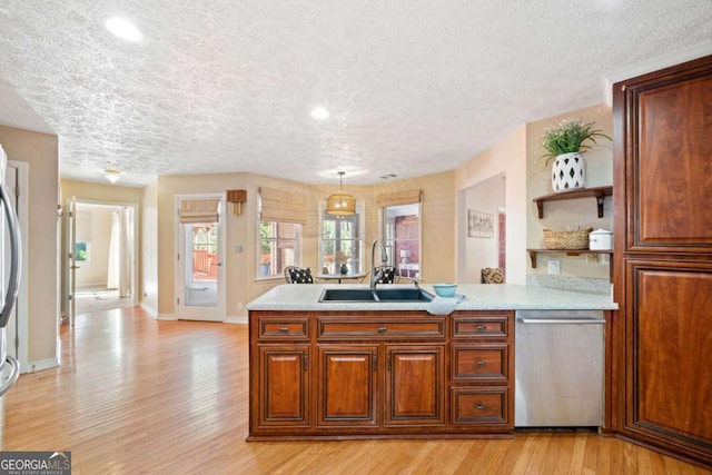 kitchen featuring decorative light fixtures, light wood-type flooring, sink, and appliances with stainless steel finishes