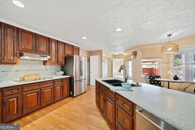 kitchen with sink, stainless steel appliances, tasteful backsplash, decorative light fixtures, and light wood-type flooring