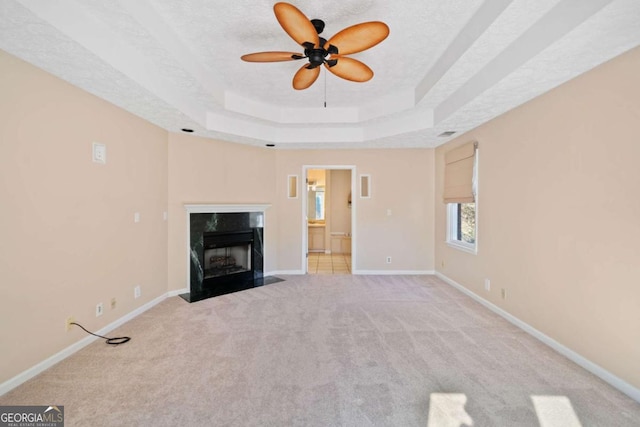 unfurnished living room with ceiling fan, a fireplace, light colored carpet, and a textured ceiling