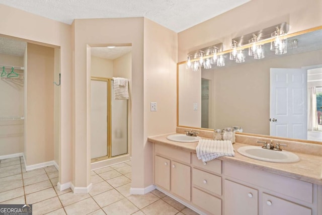 bathroom with a textured ceiling, tile patterned flooring, vanity, and an enclosed shower