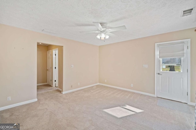 spare room with ceiling fan, light colored carpet, and a textured ceiling