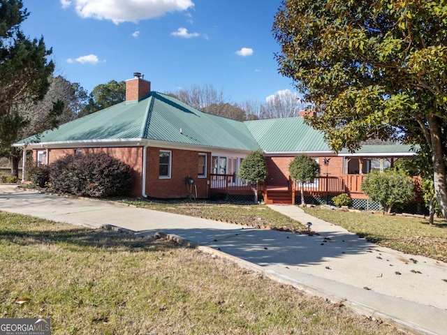 ranch-style house featuring a front lawn and a wooden deck