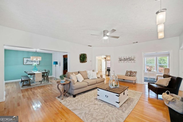 living room featuring hardwood / wood-style floors, ceiling fan, and a textured ceiling