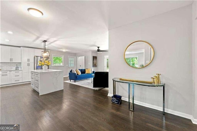 kitchen with white cabinetry, ceiling fan, hanging light fixtures, dark hardwood / wood-style floors, and backsplash