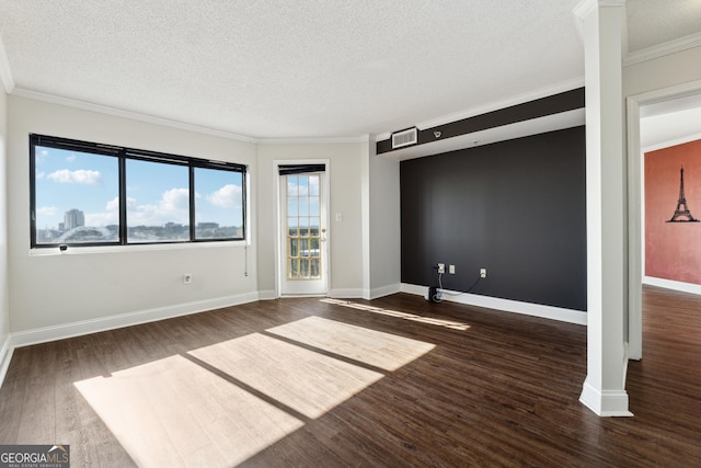 empty room featuring dark hardwood / wood-style flooring, ornamental molding, and a textured ceiling