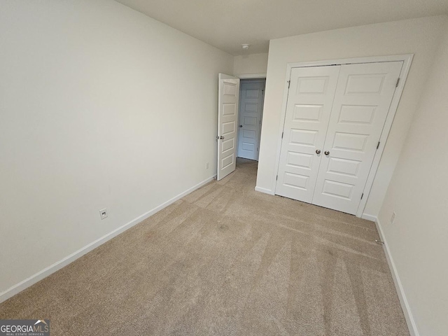 unfurnished bedroom featuring light carpet and a closet