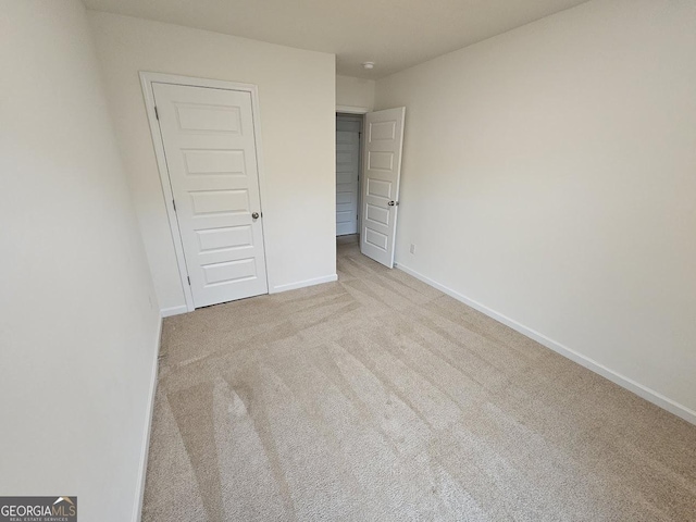 unfurnished bedroom featuring a closet and light colored carpet