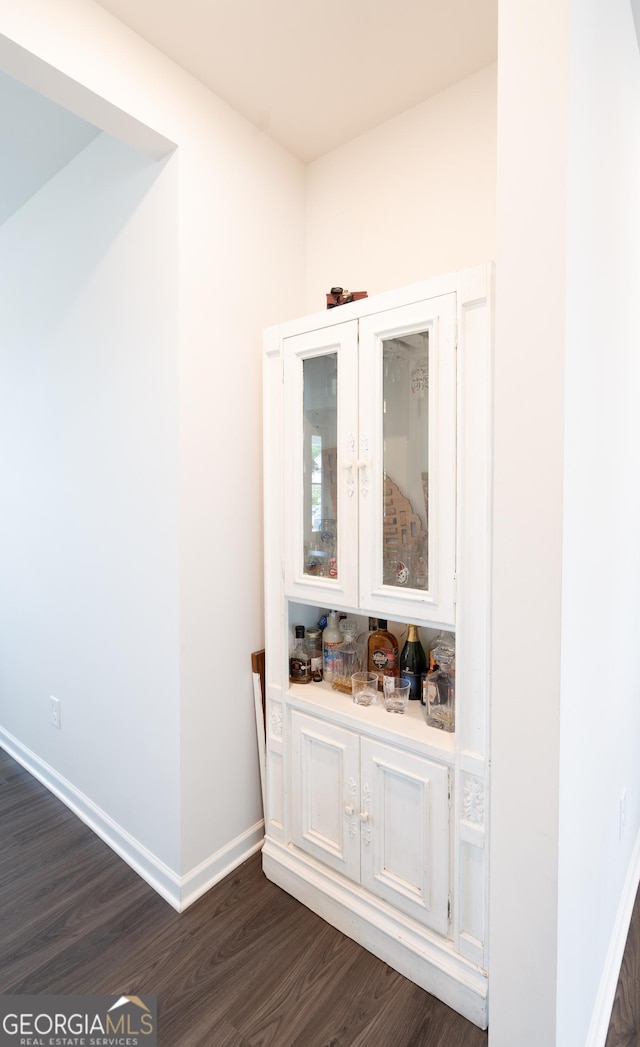 bar with white cabinets and dark wood-type flooring