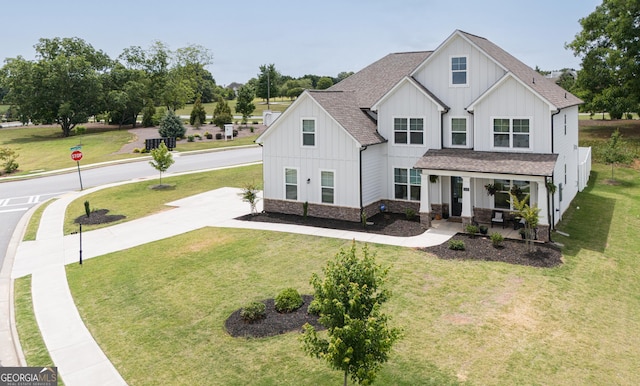 modern farmhouse with a front yard and covered porch