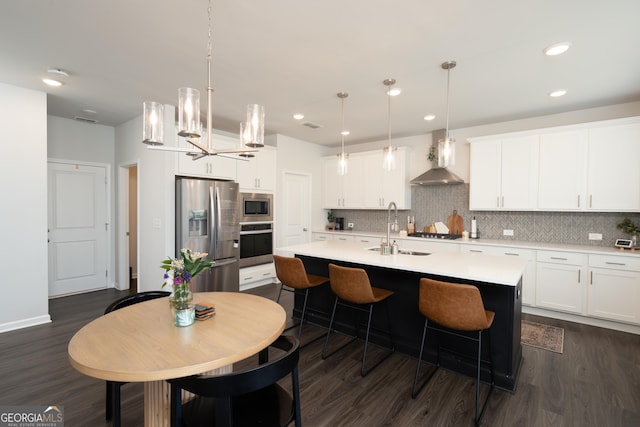 kitchen featuring stainless steel appliances, white cabinetry, a kitchen island with sink, and sink