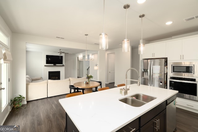 kitchen with ceiling fan, sink, stainless steel appliances, a center island with sink, and white cabinets