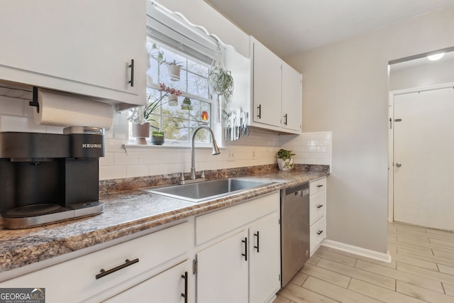 kitchen with decorative backsplash, white cabinetry, dishwasher, and sink