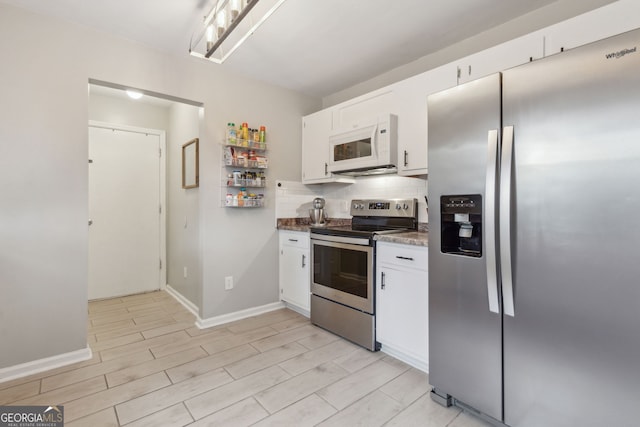 kitchen with white cabinets, decorative backsplash, dark stone countertops, light wood-type flooring, and stainless steel appliances