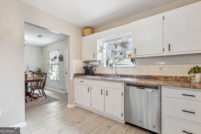 kitchen with dishwasher, white cabinets, tasteful backsplash, and sink