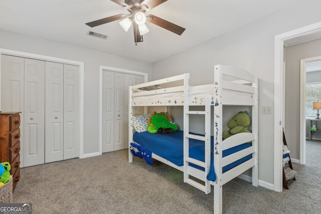 carpeted bedroom with ceiling fan and two closets