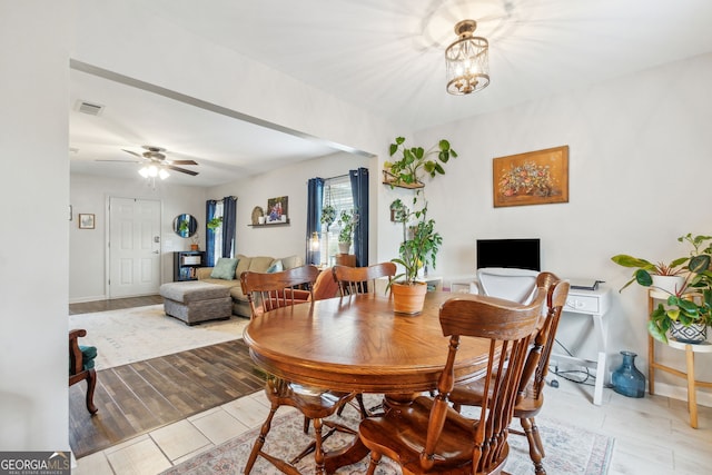 dining space featuring ceiling fan with notable chandelier