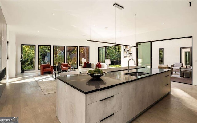 kitchen featuring a large island, sink, hanging light fixtures, and light wood-type flooring