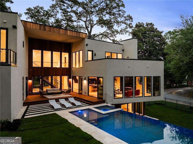 back house at dusk with a patio area, an outdoor living space, a yard, and a pool with hot tub