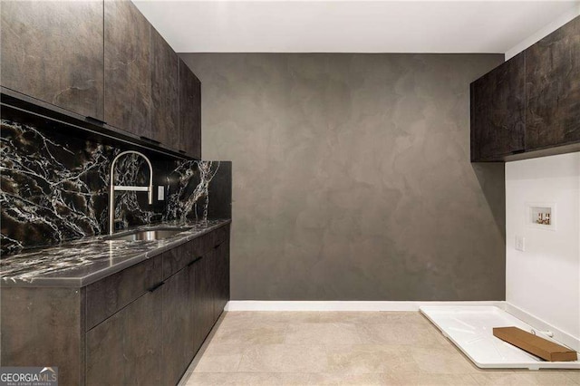 kitchen featuring decorative backsplash, dark brown cabinetry, and sink