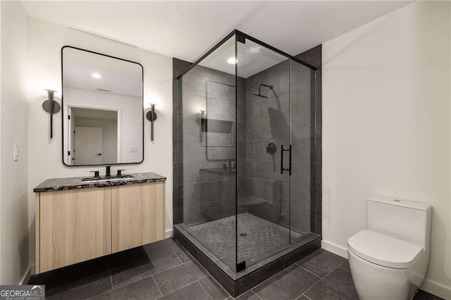 bathroom with tile patterned floors, vanity, toilet, and a shower with shower door