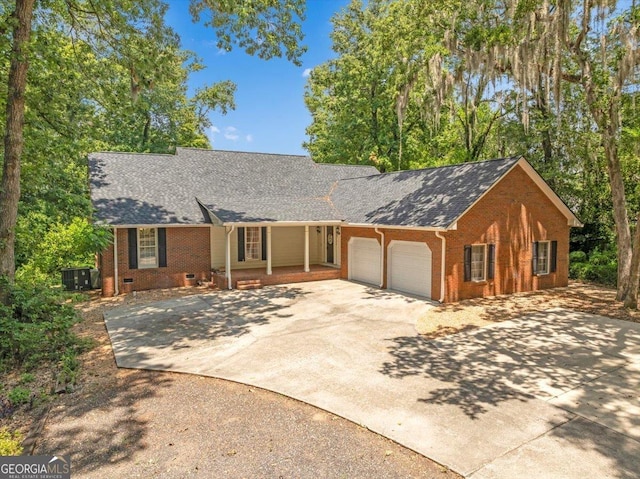 ranch-style home featuring covered porch, cooling unit, and a garage