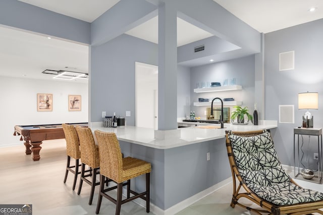 kitchen with kitchen peninsula, sink, a breakfast bar area, and billiards