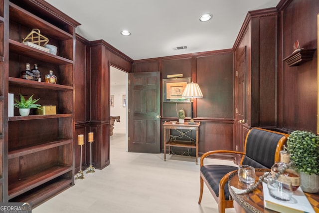 living area with crown molding and wood walls