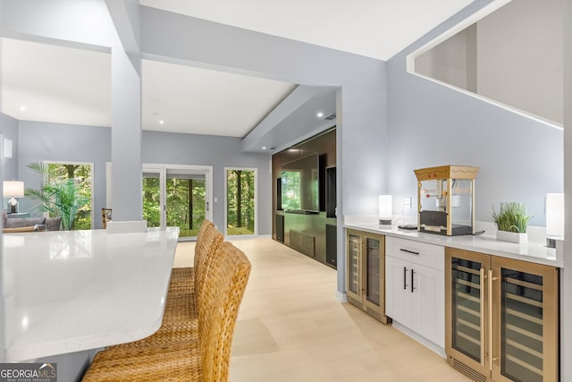 interior space with white cabinets, light stone countertops, and beverage cooler