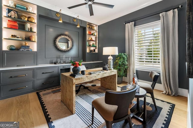 office featuring built in shelves, crown molding, ceiling fan, and light hardwood / wood-style floors