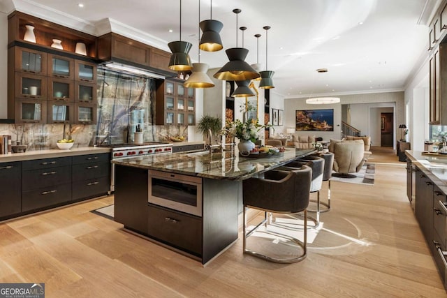 kitchen with a kitchen breakfast bar, dark brown cabinets, decorative light fixtures, dark stone countertops, and a large island