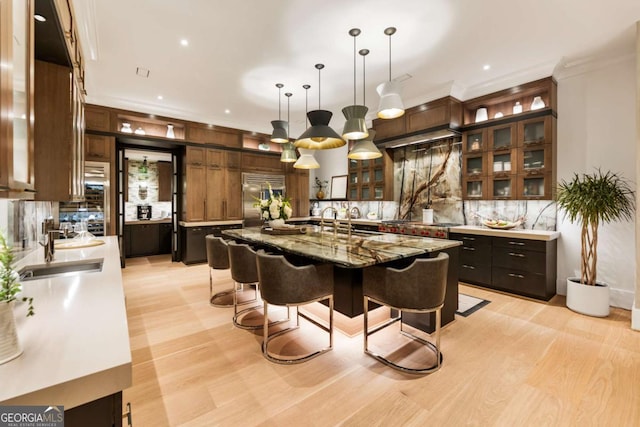 bar with light stone countertops, sink, hanging light fixtures, built in fridge, and decorative backsplash