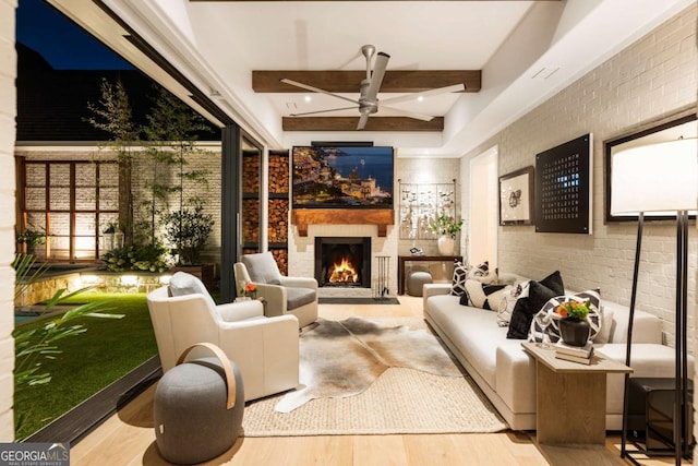 interior space featuring beamed ceiling, ceiling fan, brick wall, and light hardwood / wood-style flooring