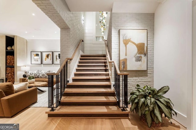 stairs featuring hardwood / wood-style floors and brick wall