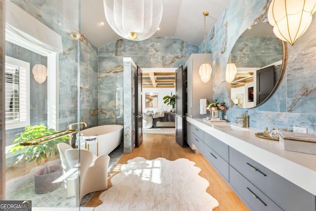 bathroom with a bathing tub, vanity, lofted ceiling, and tile walls