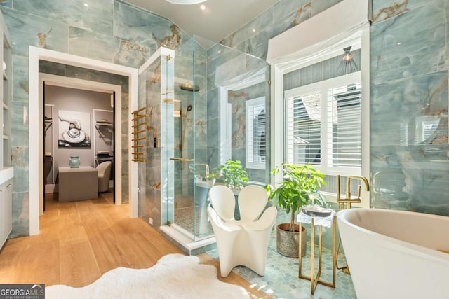 bathroom featuring hardwood / wood-style flooring, separate shower and tub, and tile walls