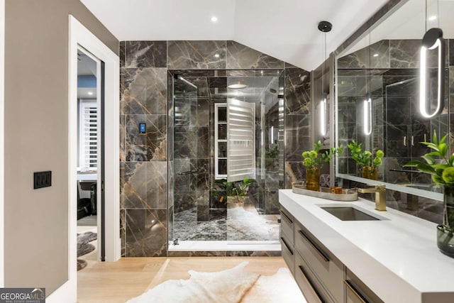 bathroom featuring a shower with door, vanity, lofted ceiling, and hardwood / wood-style flooring