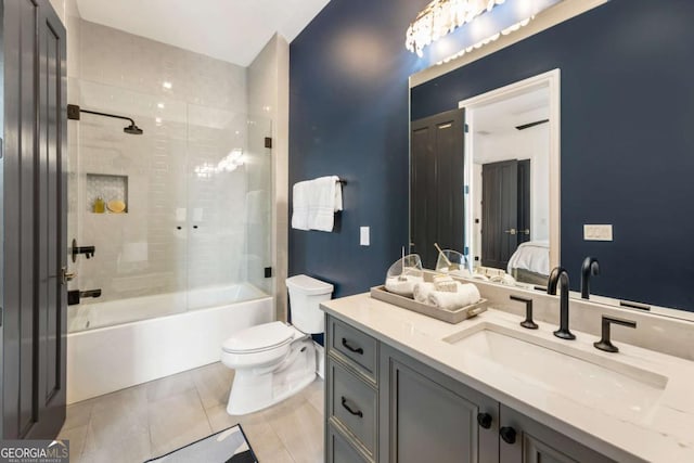 full bathroom with shower / bath combination with glass door, tile patterned floors, vanity, and toilet