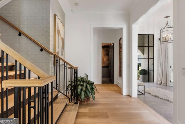 hall featuring light wood-type flooring and an inviting chandelier