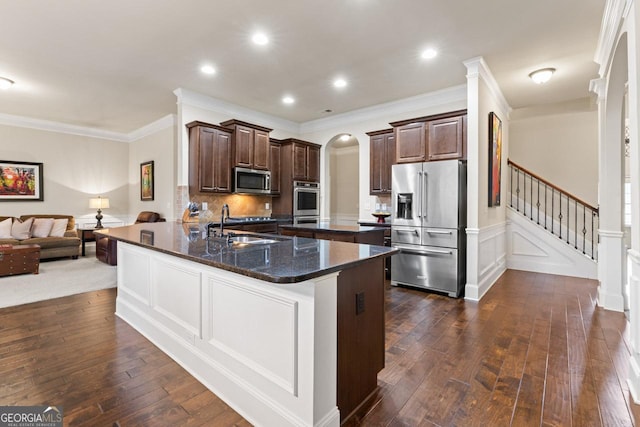 kitchen featuring sink, stainless steel appliances, kitchen peninsula, dark stone counters, and ornamental molding