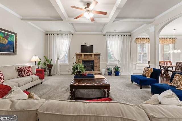 carpeted living room with coffered ceiling, ceiling fan with notable chandelier, crown molding, a fireplace, and beam ceiling