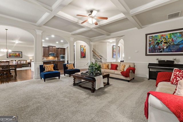 carpeted living room featuring ceiling fan with notable chandelier, beam ceiling, ornamental molding, and coffered ceiling