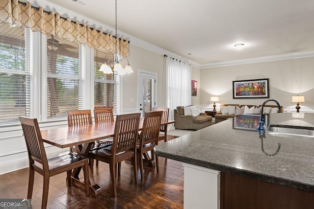 dining area featuring sink, dark hardwood / wood-style flooring, a notable chandelier, plenty of natural light, and ornamental molding