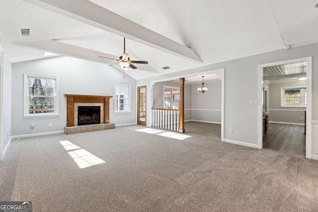 unfurnished living room with a tile fireplace, carpet, ceiling fan with notable chandelier, and a healthy amount of sunlight