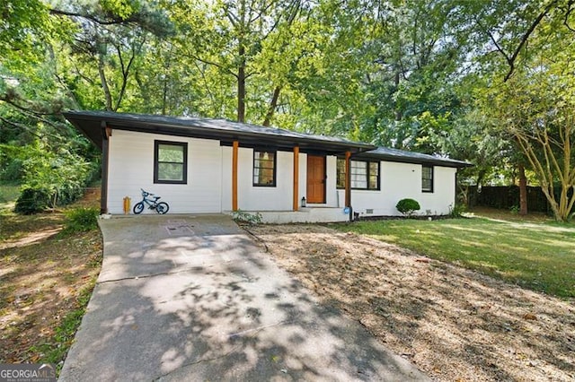 ranch-style house featuring covered porch and a front yard