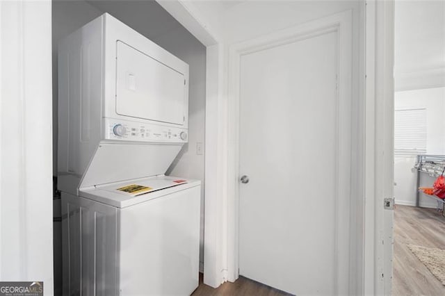 laundry room with wood-type flooring and stacked washer and clothes dryer