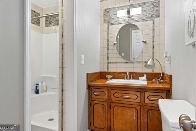 bathroom with backsplash, toilet, vanity, and walk in shower