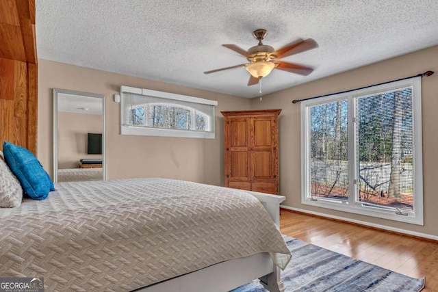 bedroom with ceiling fan, a textured ceiling, and light wood-type flooring