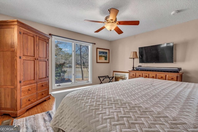 bedroom featuring ceiling fan, light wood-type flooring, and a textured ceiling