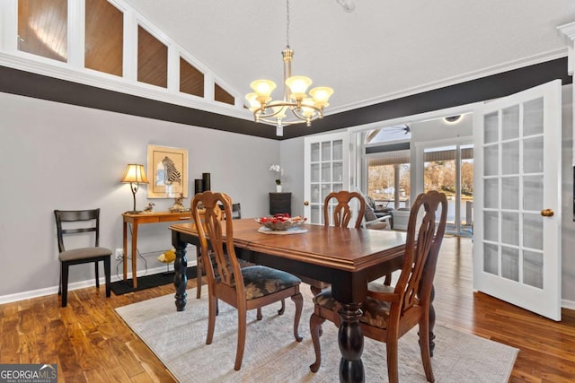 dining area featuring french doors, ornamental molding, ceiling fan with notable chandelier, hardwood / wood-style floors, and lofted ceiling