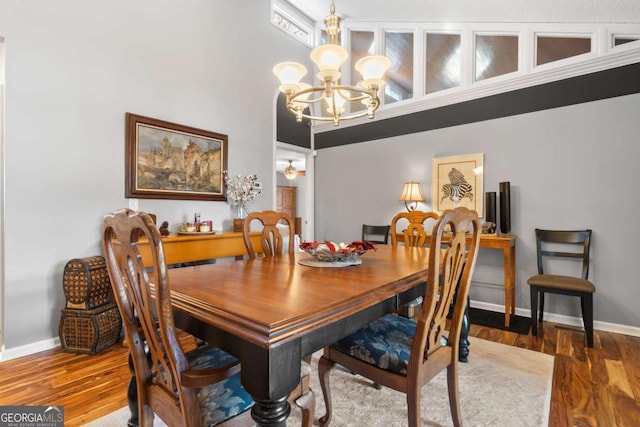 dining space with ceiling fan with notable chandelier and hardwood / wood-style flooring